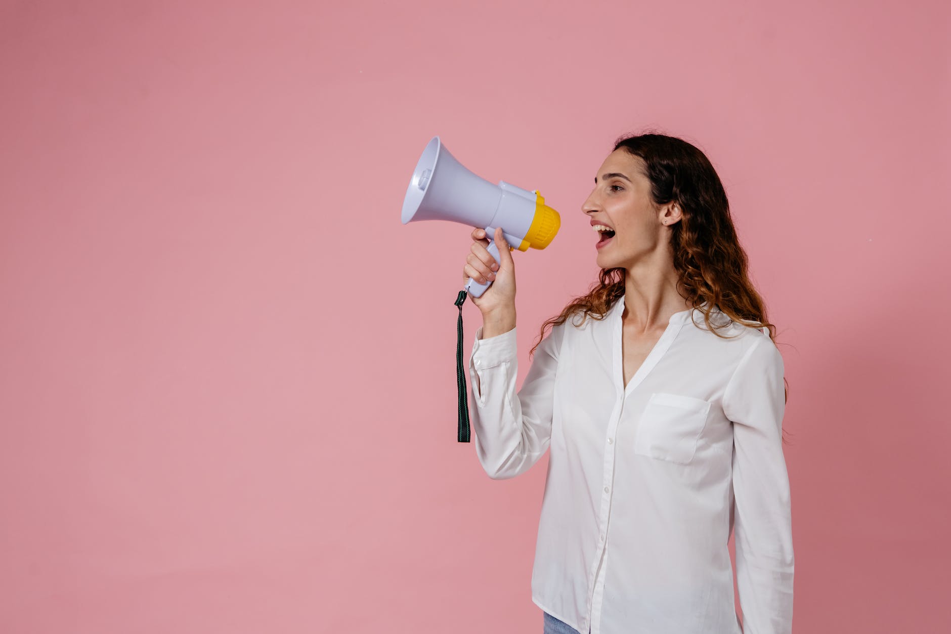 woman in white button up long sleeve shirt using a megaphone