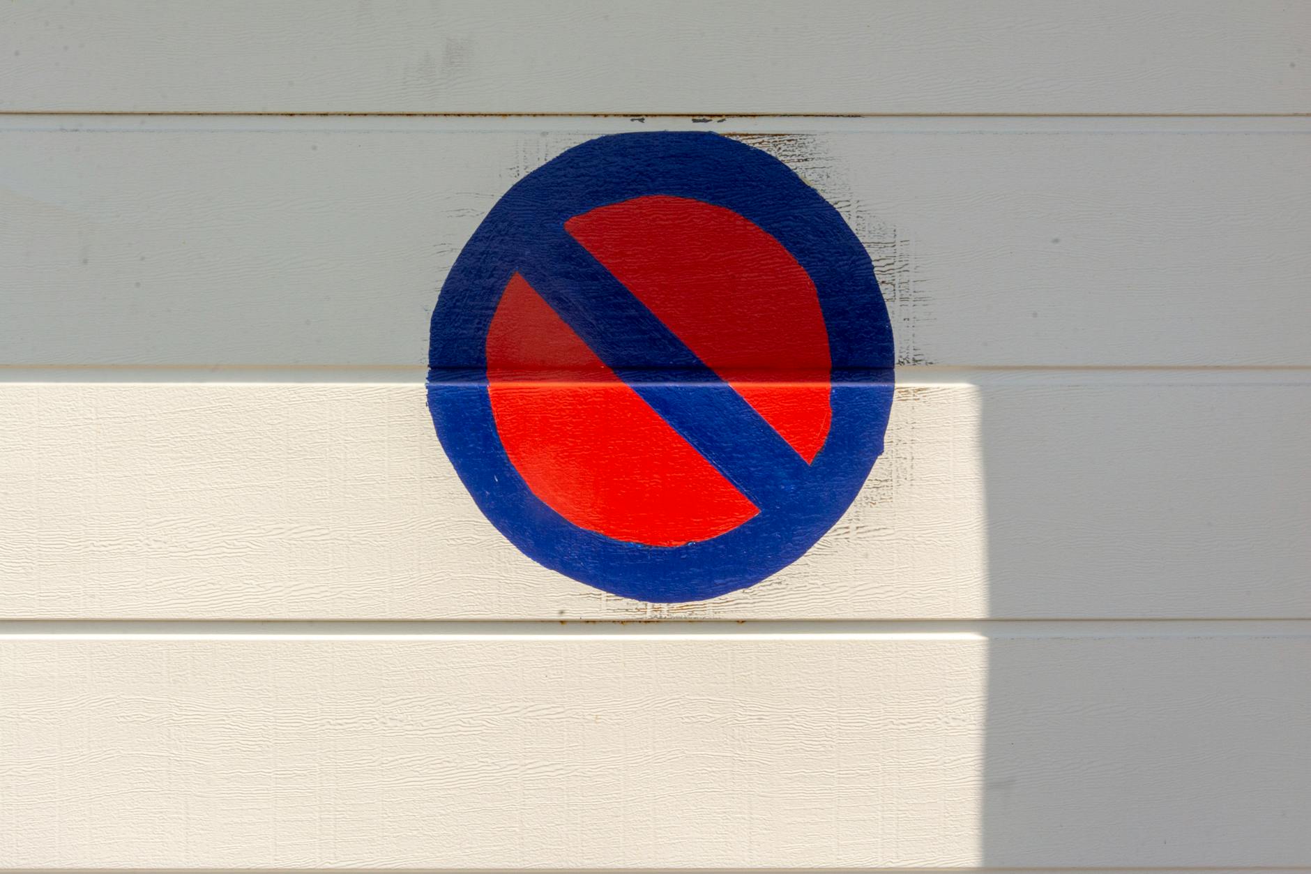 no parking sign painted on white wall with shadow