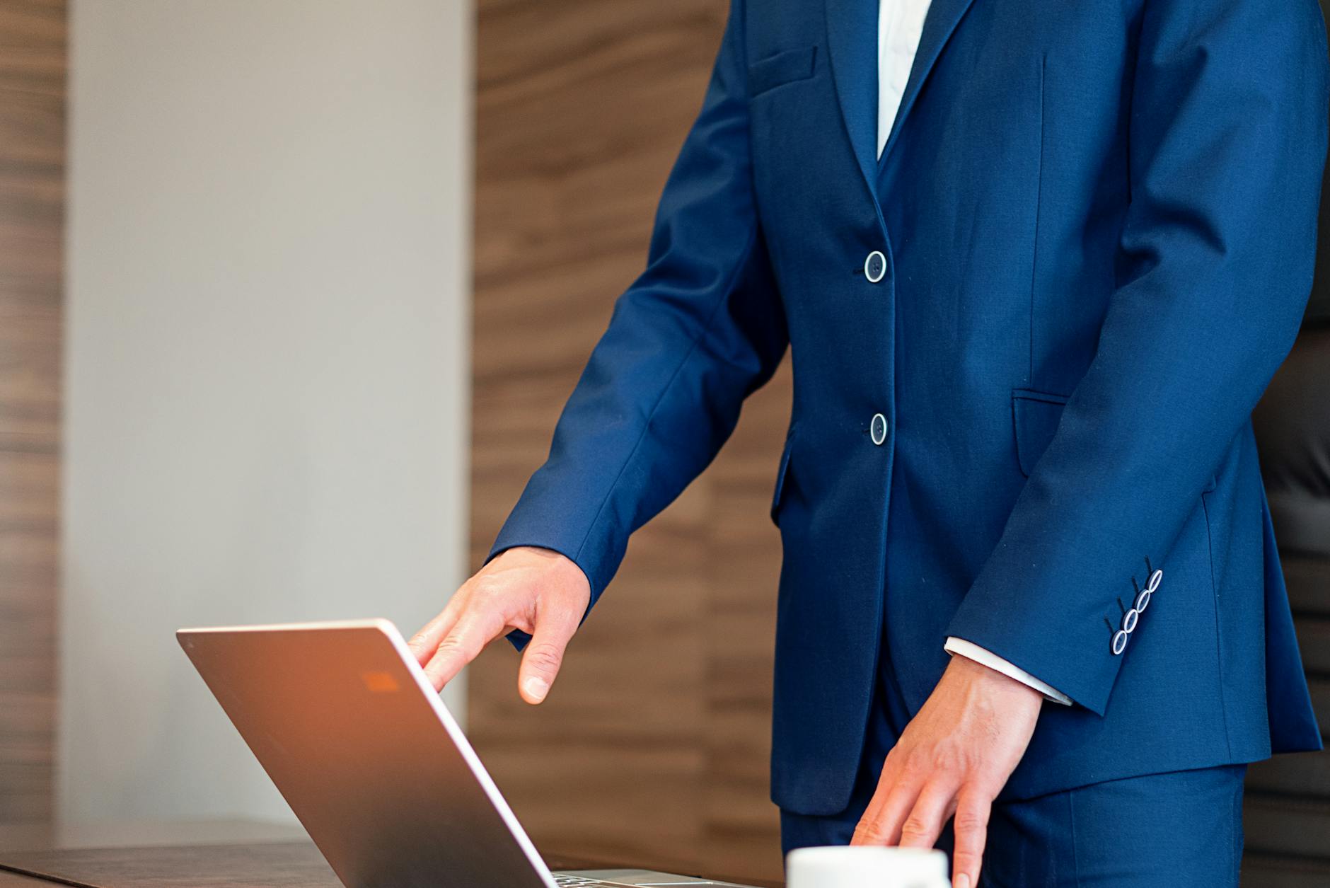 person in blue corporate attire standing and using a laptop